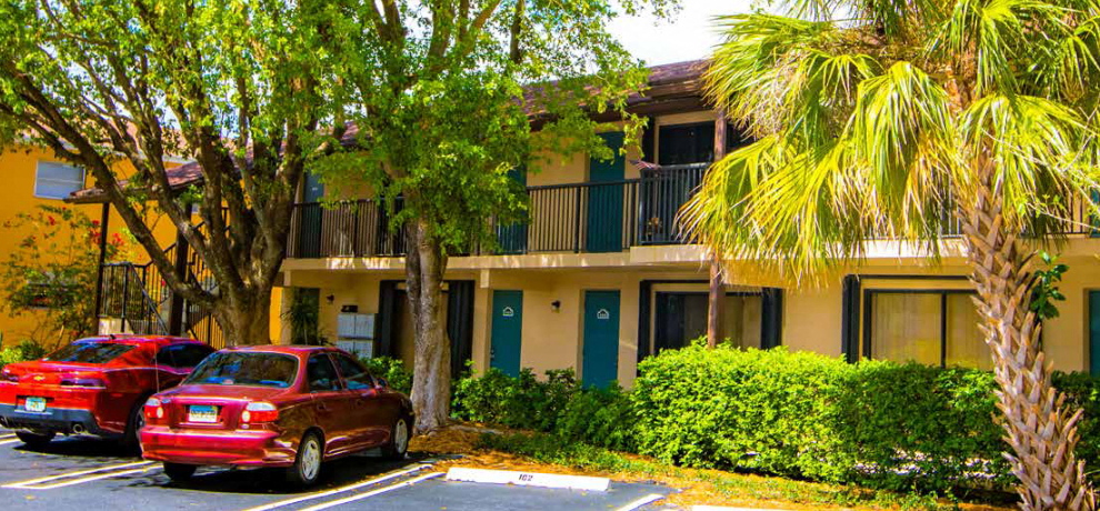 two red cars parked in front of an apartment building